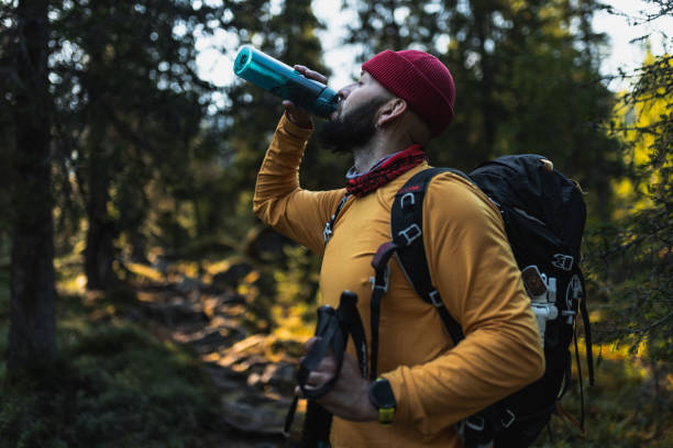 istock Man drinking water while trekking in forest wearing a backpack and winter gear 2195539887