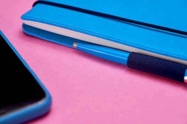 istock Close-Up of Blue Notebook and Pen on Pink Background. 2195540409