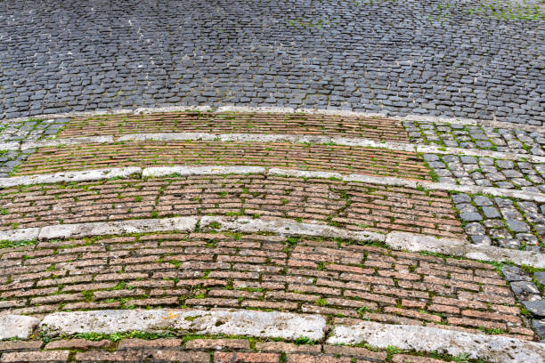 in the foreground view from the top of a wide circular stone and cobblestone staircase in the background