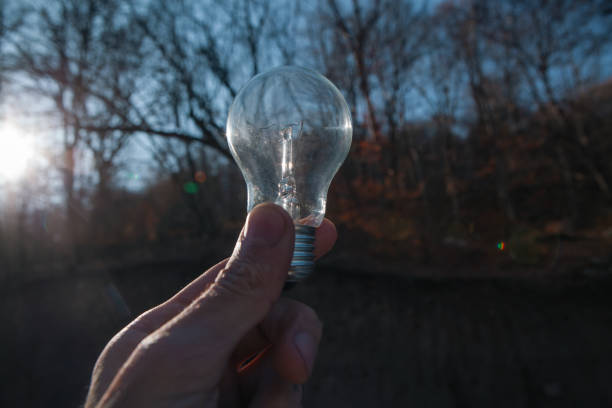 a man hand holding a bulb on background of the sky