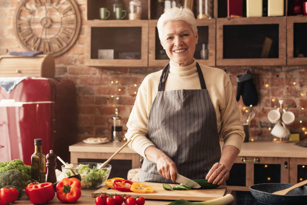 istock Cheerful senior woman cutting vegetables for salad 2195544707