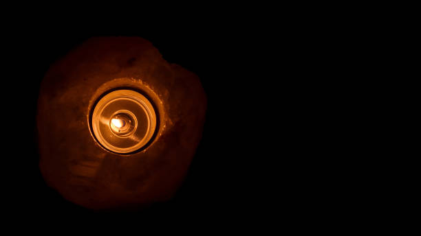A candle shines in the dark. Himalayan salt candlestick. Space for text. View from above.