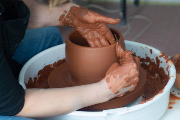 istock Female hands throwing a large sized bowl on a potter's wheel in a sunlit pottery studio 2195548261
