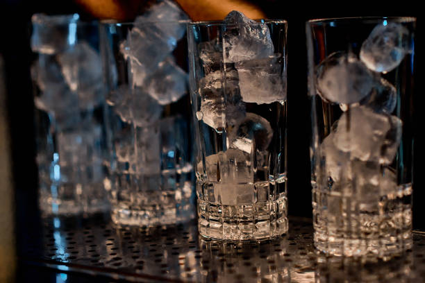 A close-up of crystal glasses filled with ice cubes, reflecting warm bar lighting, creating a luxurious and sophisticated ambiance..