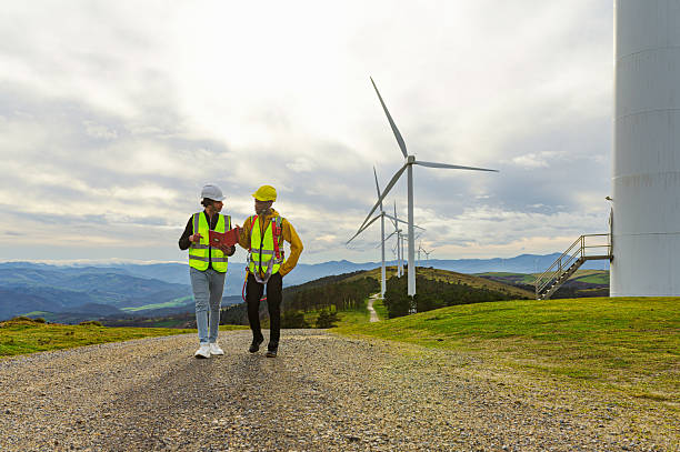 istock Engineer and operator walking and discussing in wind turbine park, inspecting green energy production 2195549778