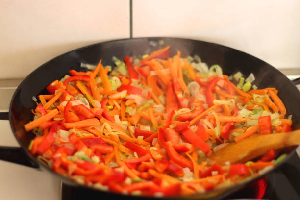 Stir frying chopped leek, carrots and red bell peppers in a wok. Selective focus.