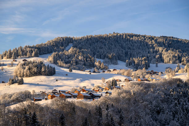 The mountain village of Schwarzenberg in the Bregenzerwald in Vorarlberg in the Austrian Alps during winter season with snowcapped mountains and forests.