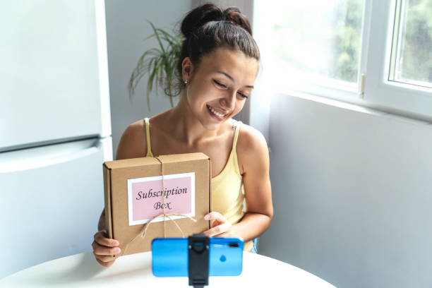 istock Young woman shows off subscription box on camera 2195560230