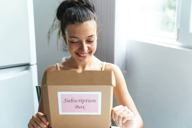 istock Woman enjoying opening a subscription box indoors happily. 2195560251