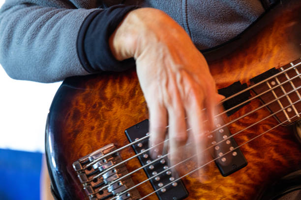 Musician practicing electric bass guitar, warming up and stretching hands exercises, closeup