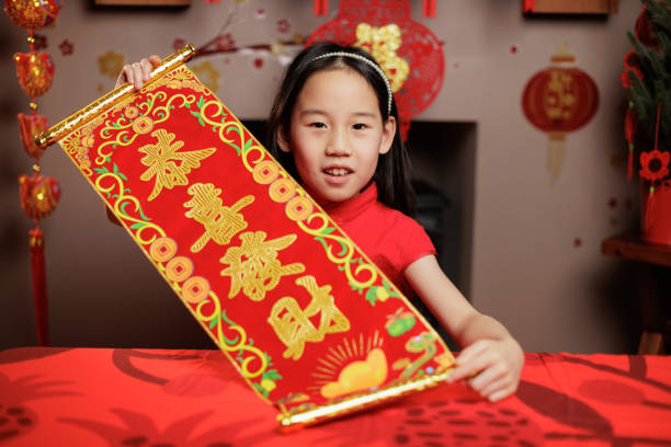 Front view of a young girl making a Lunar New Year greeting against a traditional Chinese New Year decorated background