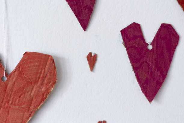 Red paper hearts hang on a white wall in the room. Cracow in Poland.