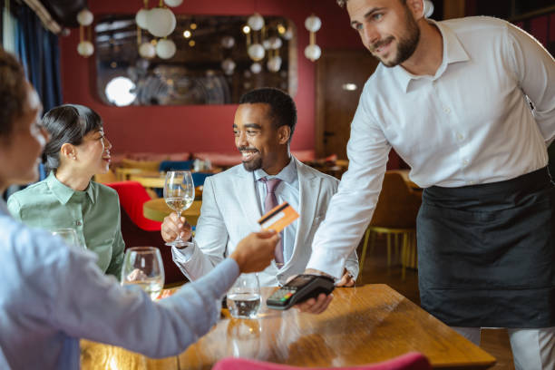 istock Diverse friends enjoy a meal together while paying with a card terminal 2195570152