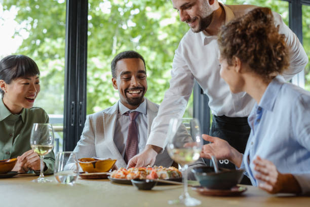 istock Diverse colleagues enjoying a meal served by a waiter in a modern restaurant 2195570210