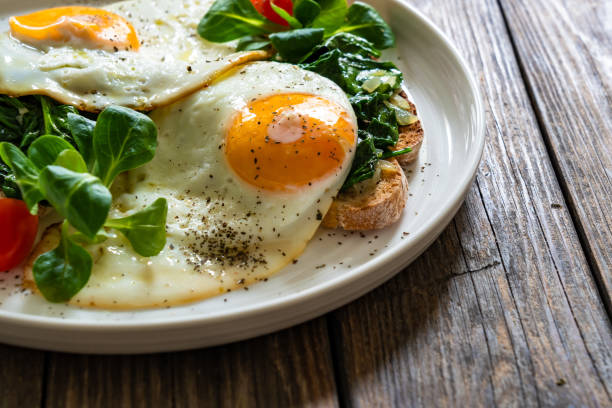 istock Crispy toast with stewed spinach and fried eggs with runny yolks on wooden table 2195570464