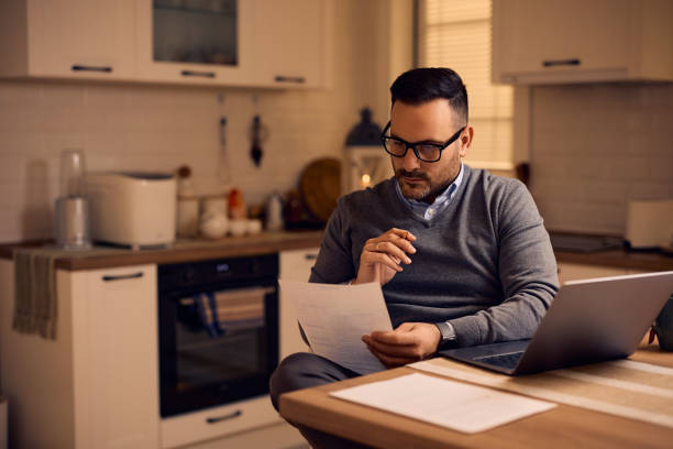 istock Mid adult entrepreneur analyzing business reports while working at home. 2195573554