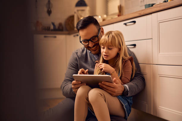 istock Father and daughter surfing the net on touchpad at home. 2195573633