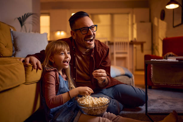 istock Cheerful father and daughter having fun while watching TV at home. 2195573761
