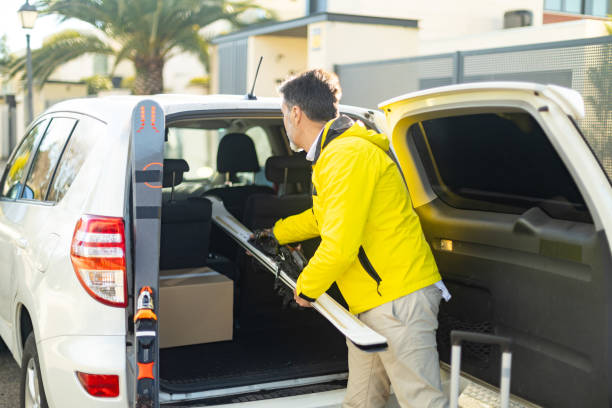 istock Courier loading skis and packages into car trunk for delivery 2195575110