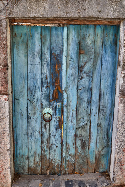Vintage wooden blue door with rustic appearance and weathered texture, set in a stone wall. Perfect for themes of history, nostalgia, and architecture.