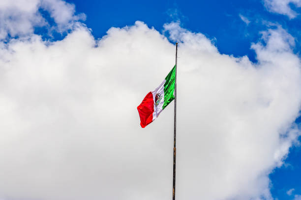 The Mexican flag waving in the wind, captured against a clear sky. The image highlights national pride, cultural identity, and patriotism, with the vibrant green, white, and red colors symbolizing Mexico’s rich heritage. Ideal for themes related to national celebrations, independence, travel, and Latin American culture.