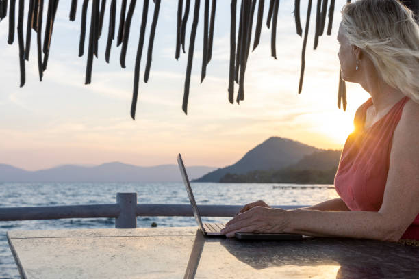 istock Mature woman works on laptop under beach palapa 2195588220