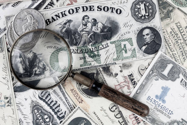 istock Retro vintage US greenback banknotes and silver certificates with silver dollar coins and magnifying glass 2195588380