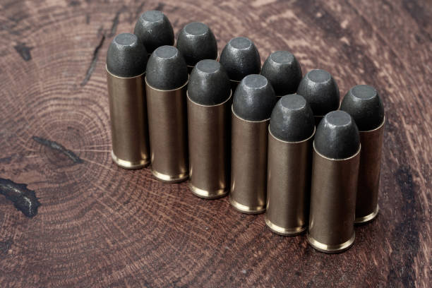 Old West era Long Colt .45 caliber revolver cartridges Old West era Long Colt .45 caliber revolver cartridges on a wooden table forty five caliber handgun stock pictures, royalty-free photos & images