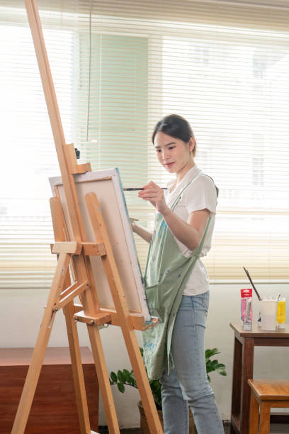 istock Young artist painting joyfully in a bright studio, showcasing creativity and passion for art 2195591764