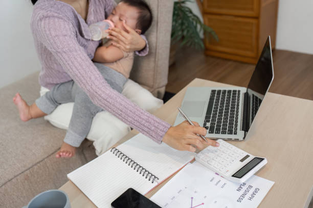 istock Dedicated mother managing finances while feeding her baby in a home office setup 2195592913