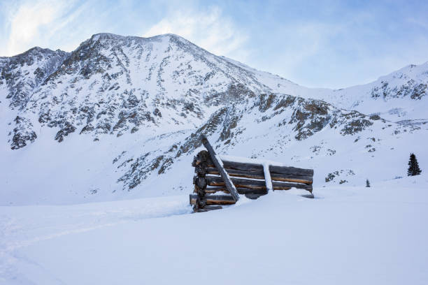 A hauntingly beautiful scene of snow-covered mountain peaks, seen from a ghost village. The lost cabin enhances the serene yet eerie atmosphere of this abandoned place, capturing the essence of nature's quiet majesty and the passage of time.