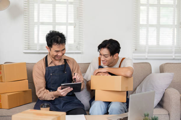 istock LGBT couple joyfully reviewing their sales progress on a tablet while packing boxes at home 2195593658