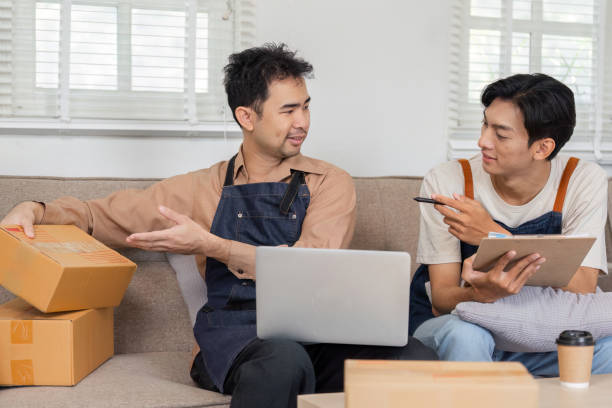 istock LGBT couple discussing online sales strategy, reviewing packaging while seated on a couch at home 2195593676