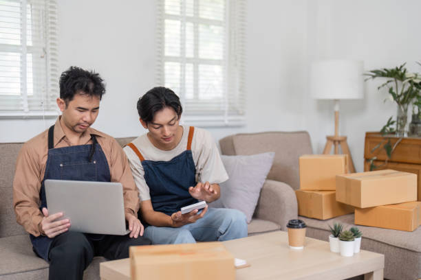 istock LGBT couple analyzing their online business data while packing orders together in their living room 2195593705