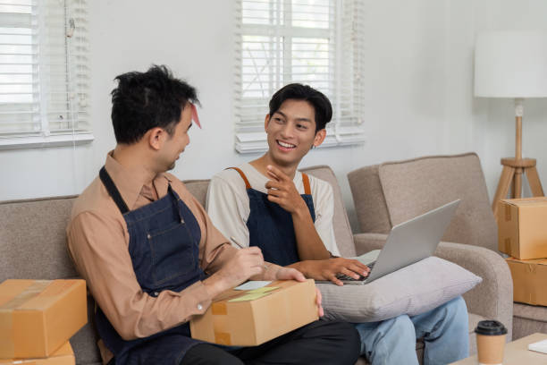 istock LGBT couple joyfully discussing online sales, sharing ideas while packing and working from home 2195593743
