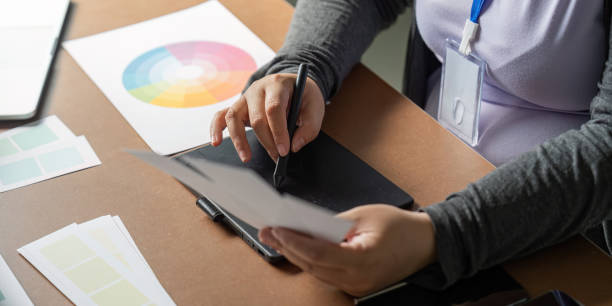 istock Graphic designer sketching ideas on a tablet while examining color palettes at her desk 2195595448