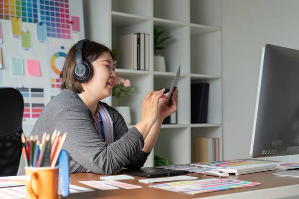 istock Graphic designer engaged in digital design work while wearing headphones in a modern creative workspace 2195595521