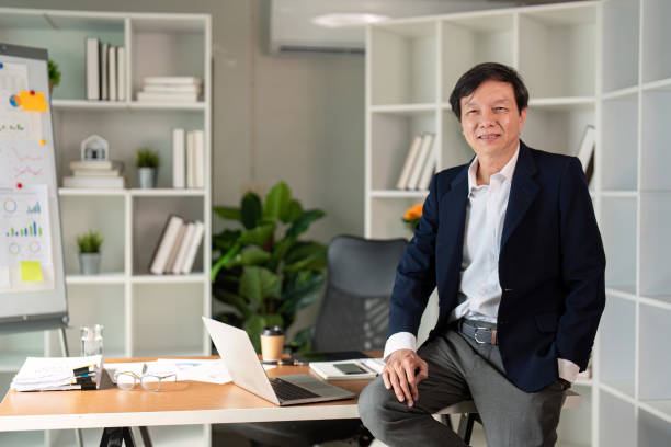 istock Elderly businessman confidently seated at desk in modern office environment. 2195596776