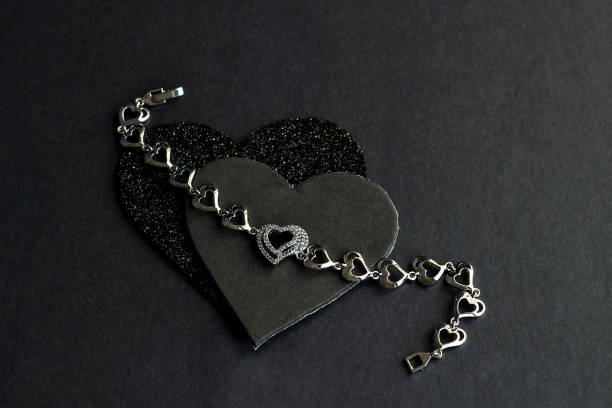 Top view of diamond female wristband on the two dark hearts at the black background.