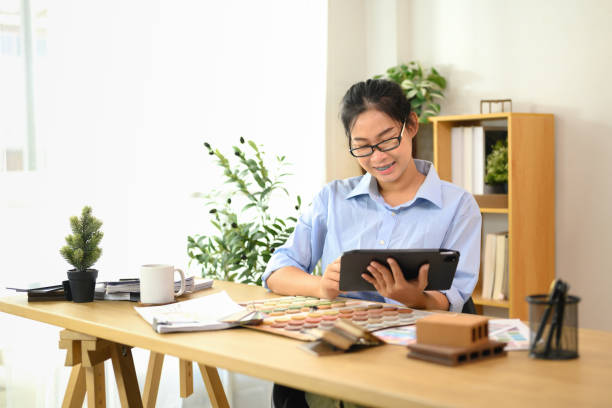 istock Smiling interior designer using digital tablet at working desk with color swatches, material samples and design tools 2195619851