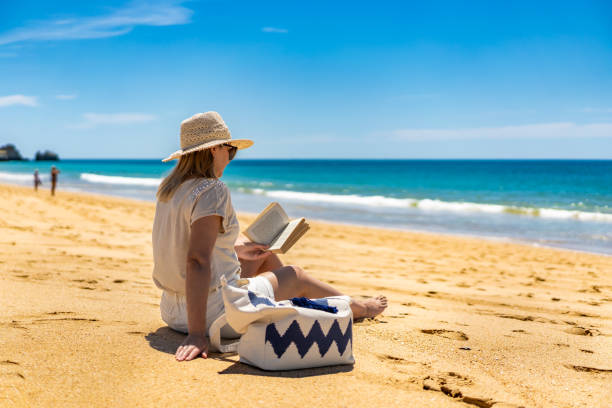 istock Beautiful mature woman sitting on sandy beach 2195620280