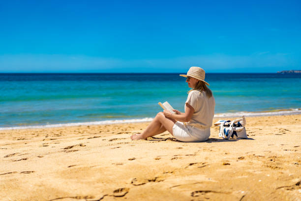istock Beautiful mature woman sitting on sandy beach 2195620294