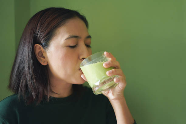 istock Close-up Woman face drinking a vegetable and fruit smoothie 2195621074