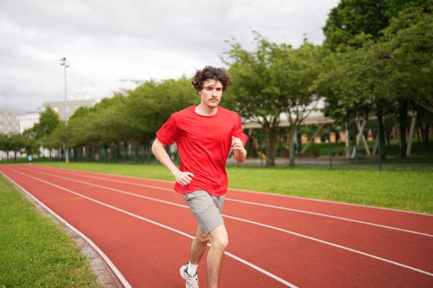 istock Young man running along a professional running track outdoors 2195622949