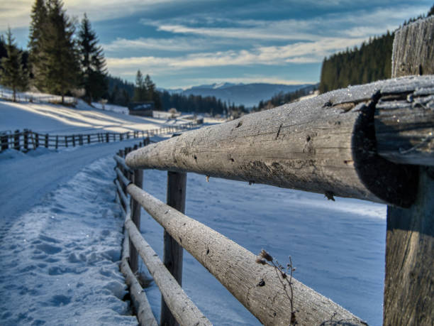 Panoramic view over a snow fence over snow covered fields, villages and hills to the Allgäu Alps, Bavaria, Germany in winter.