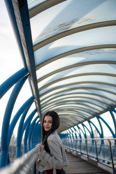 istock Young woman posing on modern pedestrian bridge with curved roof 2195632184