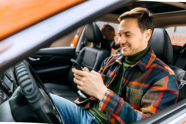 istock Handsome casually clothed man using his phone while sitting in a car 2195632752