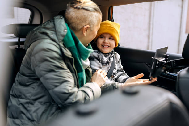 istock Mother and son having fun while riding on back seat of car 2195632764