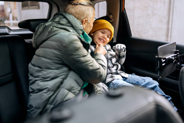istock Mother and son having fun while riding on back seat of car 2195632786