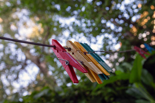 Washing line with wooden clothespin and garment against blurred background, closeup